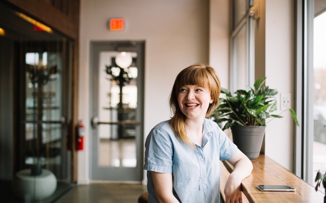 Image of a woman sat at a table smiling