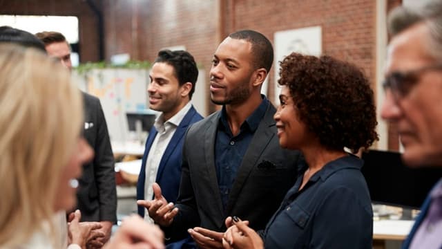 A group of business owners of different genders, ethnicities and backgrounds networking in a room